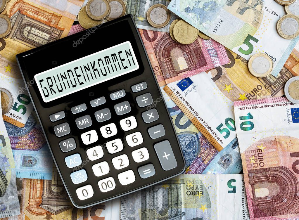 German word GRUNDEINKOMMEN, basic income, written on display of pocket calculator against cash money on table