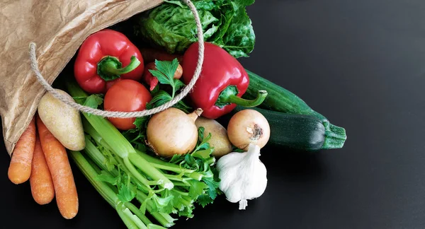 Fresh organic vegetables bought on weekly market in brown paper bag against dark table background — Stock Photo, Image