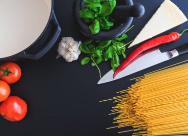 harç, domates, sarımsak, biber ve Parmesan peyniri karanlık mutfak tezgahı üzerinde taze fesleğen ile İtalyan makarna hazırlama