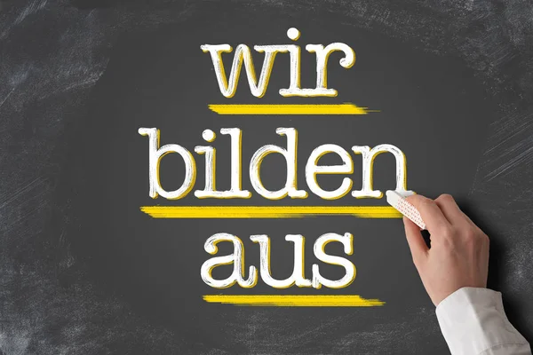 Текст Wir Bilden AUS, німецька для нас поїзд учнів, на дошці — стокове фото