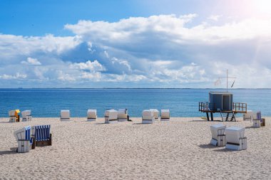 mavi deniz ve gökyüzüne karşı geniş kum plajda plaj sandalyeleri ve cankurtaran kulesi