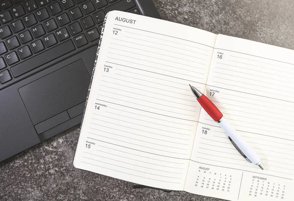Öppna kalender eller planerare och penna på en bärbar dator — Stockfoto
