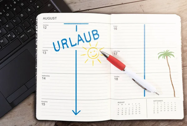 Calendar on table with word URLAUB, German for vacation, and sun icon against wooden table — Stok fotoğraf