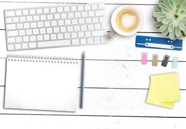 Modern ofis çalışma alanı, bilgisayar klavyeli ahşap masa, not defteri, kahve kupası ve ofis malzemeleri.