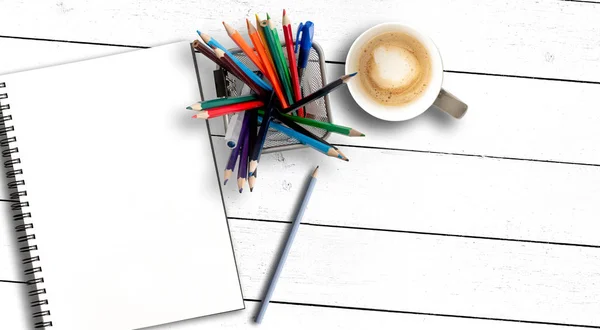 Vak gevuld met gekleurde potloden en schetsboek of spiraal Kladblok op rustieke witte houten tafel — Stockfoto
