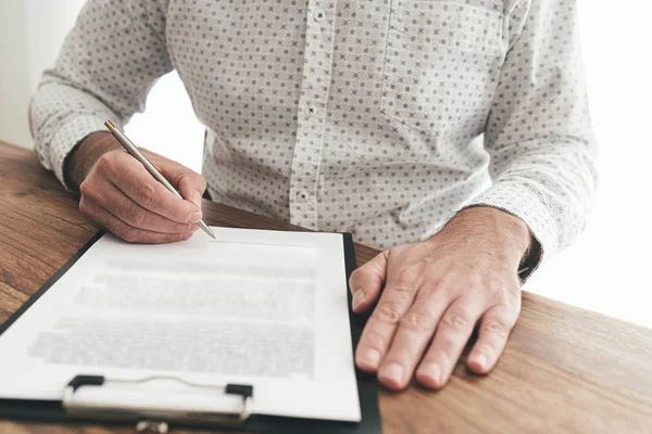 Hombre de negocios sentado en el escritorio de madera firmar documento o contrato — Foto de Stock