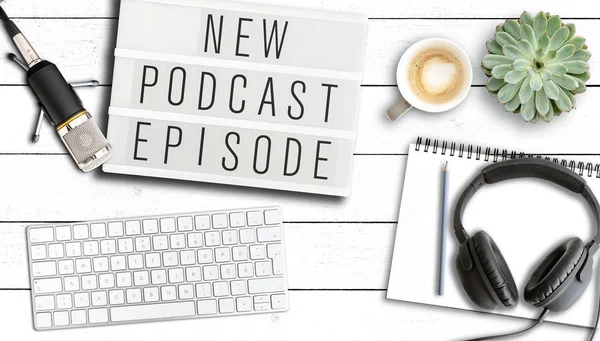 podcasting kavramı, kelimeler Yeni Podcast Episode mikrofon ve bilgisayar klavyesi ile masada ışık kutusu