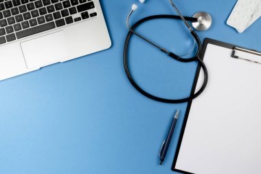 Steteskoplu, dizüstü bilgisayarı ve panosu olan doktor ya da hekimin masası