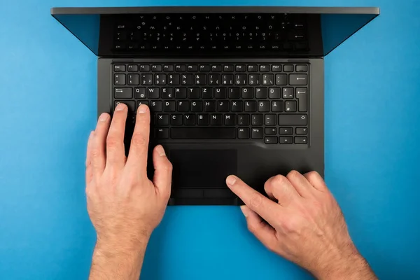Uomo che utilizza computer portatile su sfondo blu scrivania — Foto Stock