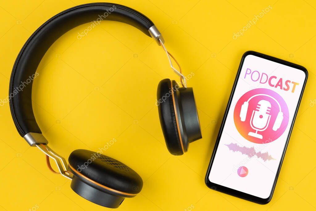 Podcasting concept, above view of headphones and smartphone with podcast player mockup on yellow background