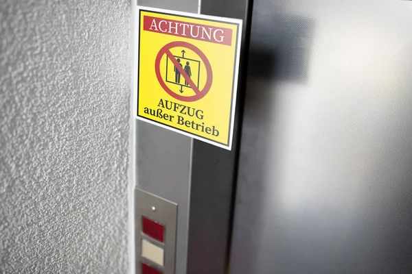 Жовтий службовий знак з німецьким текстом для ELEVATOR's OUT of SERVICE прикріплений до дверей ліфта — стокове фото