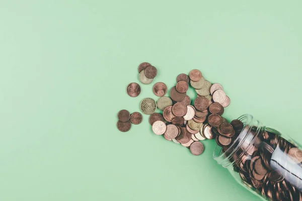 above view of small change Euro coins spilling out of glass jar