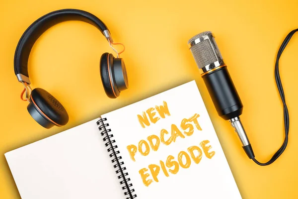 NEW PODCAST EPISODE text on notepad next to headphones and recording microphone — Stock Photo, Image