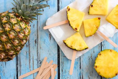 Ananas dilim çubuklu dondurmayı. Üstten görünüm tablo sahne mavi ahşap arka plan üzerinde.