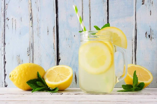 Homemade lemonade in a mason jar glass. Side view on a rustic blue wood background.