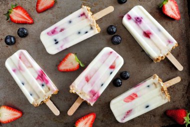 Ev yapımı karışık berry yoğurt dondurmayı granola ile grubudur. Karanlık bir arka plan üzerinde üstten görünüm.