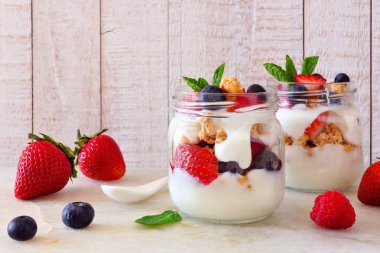 Çilek, yaban mersini ve ahududu gezegendeki mason kavanoz. Yan görünümü sahne parlak ahşap zemin üzerine.