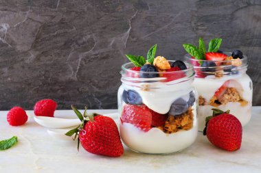 Sağlıklı çilek, yaban mersini ve ahududu gezegendeki mason kavanoz. Yan görünümü sahne.