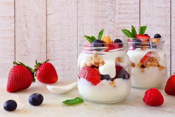 Çilek, yaban mersini ve ahududu gezegendeki mason kavanoz. Yan görünümü sahne parlak ahşap zemin üzerine.