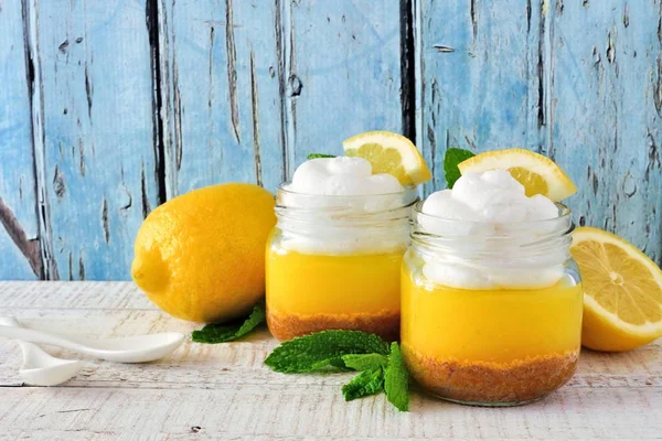 Homemade lemon pie with whipped cream in mason jars against a blue wood background
