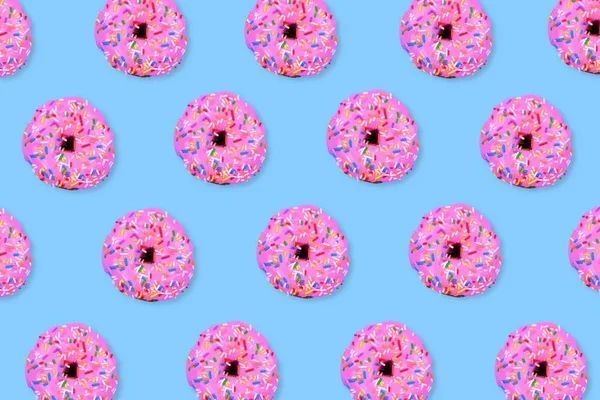 Colorful food pattern. Soft pink iced donuts on a pastel blue background. Top view.