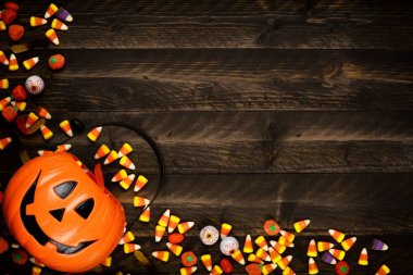 Halloween Jack o fener kova şeker dökülüp, köşe sınır. Kopya alanı bir rustik ahşap zemin üzerine görünümünün üst.