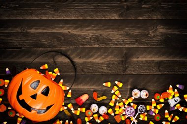 Halloween Jack o fener kova şeker dökülüp, alt kenarlığı olan. Kopya alanı bir rustik ahşap zemin üzerine görünümünün üst.