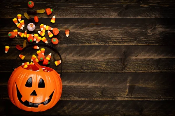 Halloween Jack o fener kova şeker dökülüp, yan sınır. Kopya alanı bir rustik ahşap zemin üzerine görünümünün üst.