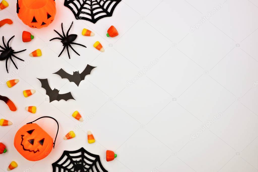 Halloween side border of scattered candy and decor. Flat lay over a white background. Copy space.