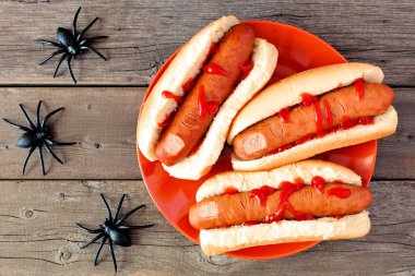 Ürpertici Halloween sosis parmak bir rustik eski ahşap arka plan üzerinde turuncu bir plaka üzerinde