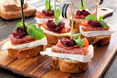 Tatil crostini meze kızılcık sosu, brie, salam ve nane ahşap bir sunucu üzerinde