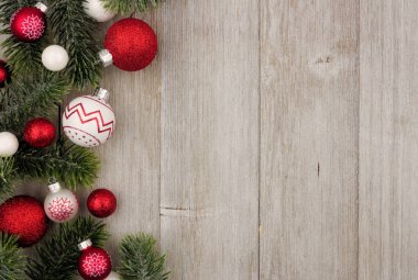 Kırmızı ve beyaz baubles rustik gri ahşap arka plan ağaç dalları ile Noel yan sınır