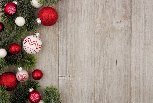 Kırmızı ve beyaz baubles rustik gri ahşap arka plan ağaç dalları ile Noel yan sınır