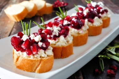 Tatil crostini meze kızılcık, nar ve beyaz peynir ile. Bir servis tabağı ahşap bir arka plan üzerinde Kapat.
