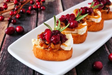 Kızılcık, brie ve karamelize soğan ile crostini meze. Bir servis tabağı ahşap bir arka plan üzerinde Kapat.