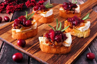 Kızılcık, brie ve karamelize soğan ile crostini meze. Tablo sahne ahşap bir tepside kapatın.