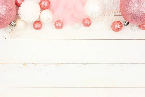 柔和的粉红色圣诞装饰顶部边框在明亮的白色木头背景 — 图库照片