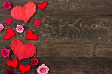 Sevgililer günü yan kenarlığını ahşap kalpler ve kağıt çiçekler koyu ahşap arka plan karşı. Kopya alanı.
