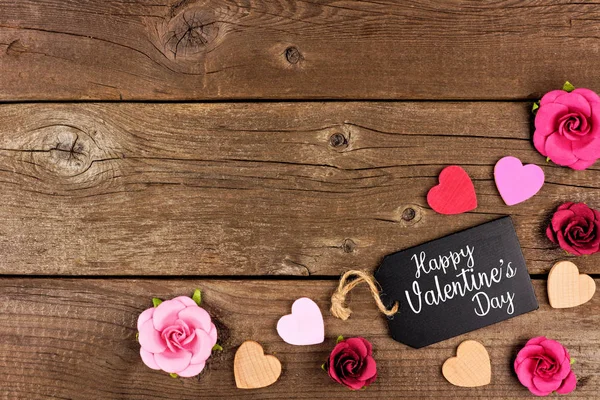 Mutlu sevgililer günü köşe sınır hediye etiketi, ahşap kalpleri ve kağıt gül bir rustik ahşap arka plan ile. Kopya alanı.