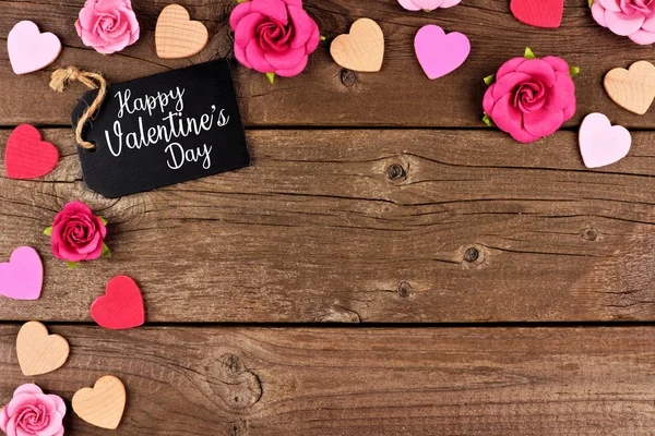Mutlu sevgililer günü köşe sınır hediye etiketi, ahşap kalpleri ve kağıt gül bir rustik ahşap arka plan ile. Kopya alanı.