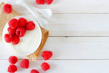 Ahududu ile sağlıklı yoğurt. Beyaz ahşap zemin üzerinde genel gider yan sınır. Kopya alanı.