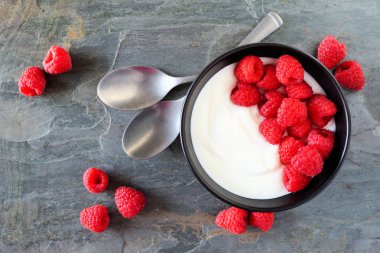 Kase Yoğurt ile ahududu. Üstten görünüm, tablo sahne karanlık arduvaz arka plan üzerinde.