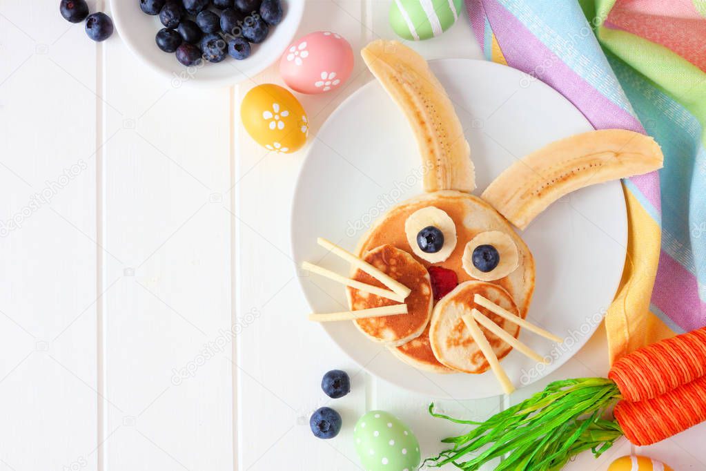 Fun Easter Bunny pancakes on a white plate. Corner border against a white wood background with copy space.