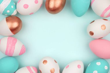 Paskalya çerçeve pembe, beyaz, mavi ve gül altın Paskalya yumurta pastel mavi bir arka plan karşı. Kopya alanı ile Üstten Görünüm.