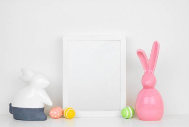 Paskalya yumurtaları ve modern Paskalya bunny dekor bir raf veya Resepsiyon ile beyaz çerçeve kadar alay et. Paskalya kavramı. Beyaz renk düzeni. Dikey Çerçeve yönlendirme.