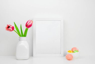 Paskalya yumurtaları ve Lale çiçek bir raf veya Resepsiyon ile beyaz çerçeve kadar alay et. Paskalya kavramı. Beyaz renk düzeni. Dikey Çerçeve yönlendirme.