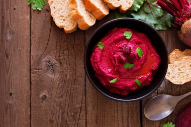 Pancar humus daldırma, rustik ahşap arka planda ekmek ve malzemelerle üst görünüm köşe kenarlık. Boşluk Kopyala.