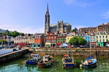 Cobh, County Cork, Irlanda limanındaki arka planda Katedral ile renkli binalar ve eski tekneler