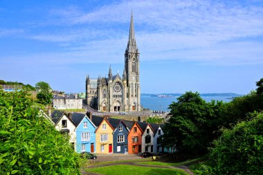 Cobh, County Cork, Irlanda liman kasabasında arka planda yükselen Katedral ile renkli sıra evler