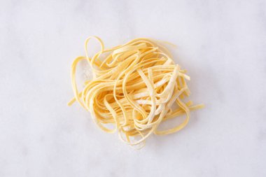 Taze Linguine makarna, beyaz mermer arka planda üst görünüm yuva